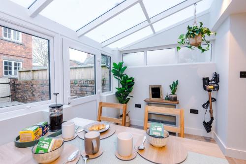 a living room with a table and two windows at Foden's House by YourStays - 2 Bedroom Cottage in Sandbach with gorgeous dining room extension, High end finish in Sandbach