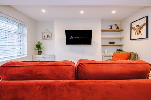 a living room with a red couch and a flat screen tv at Foden's House by YourStays - 2 Bedroom Cottage in Sandbach with gorgeous dining room extension, High end finish in Sandbach