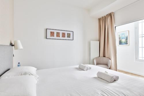 een witte slaapkamer met een bed en een stoel bij Marais Elegence Suites - Two bedrooms in Parijs