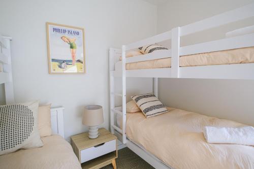 a bedroom with two bunk beds and a lamp at Oceanview Escape - Luxe Coastal Retreat with Hot Tub in Surf Beach
