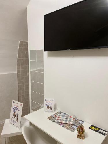 a television on a wall above a table with books at Room 416 - Affitti Brevi Italia in Monte SantʼAngelo