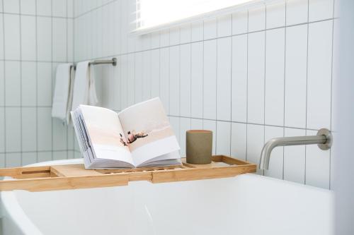 a book sitting on a shelf in a bathroom at Oceanview Escape - Luxe Coastal Retreat with Hot Tub in Surf Beach