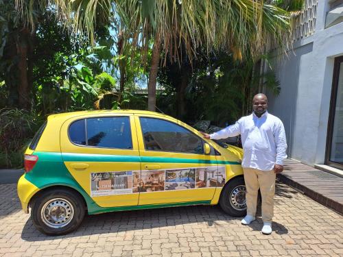 a man is standing next to a small car at Joli Guesthouse in Maputo