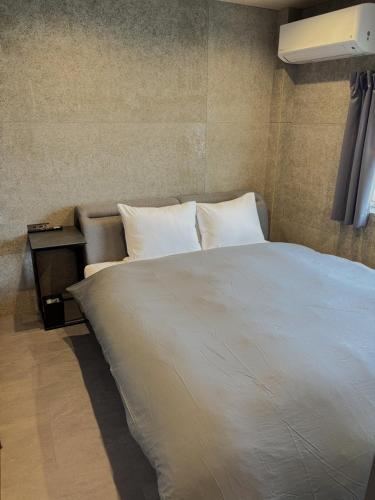 a bedroom with a large white bed and a night stand at B-sum M-1 in Matsuzaka