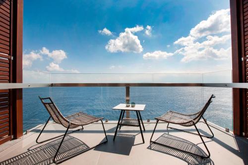 2 sedie e un tavolo sul balcone con vista sull'oceano di Aquila Elounda Village Resort, Suites & Spa a Eloúnda