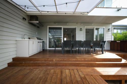 a patio with a table and chairs on a deck at Oceanview Escape - Luxe Coastal Retreat with Hot Tub in Surf Beach