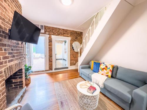 a living room with a blue couch and a brick wall at Serenity home in the heart of city in Sydney