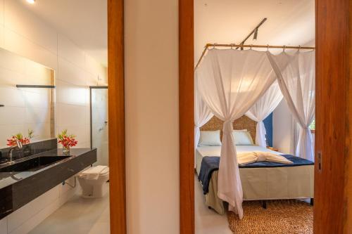 a bedroom with a canopy bed and a bathroom at Bahia Soul - Morada Garú - Taipu de Fora - Península de Maraú in Taipu