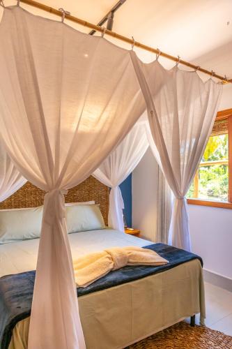 a bedroom with a canopy bed with curtains at Bahia Soul - Morada Garú - Taipu de Fora - Península de Maraú in Taipu