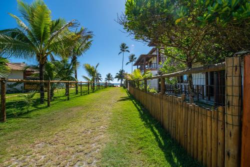 a fence in front of a house with palm trees at Bahia Soul - Morada Garú - Taipu de Fora - Península de Maraú in Taipu