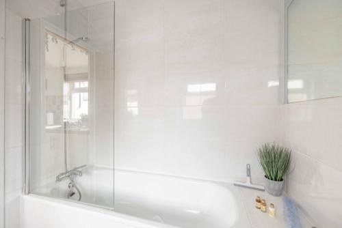 a white bathroom with a tub and a glass shower at 2BR Character Home Minutes from Windsor, Private Garden - By Tempstay in Windsor