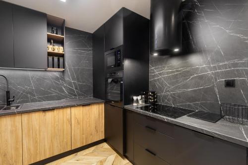 una cucina con ripiani in granito nero e armadi in legno di Apartament Larice VIP - sauna, balia, basen a Świeradów-Zdrój