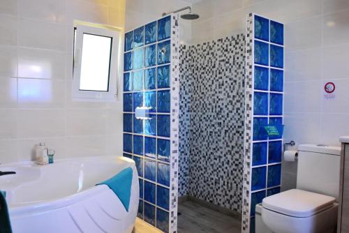 a bathroom with a tub and a toilet and a sink at Pear Tree Cottage in Lixouri