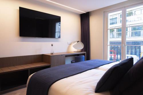 a bedroom with a bed with a tv on the wall at 1.75 Paris La Source in Paris