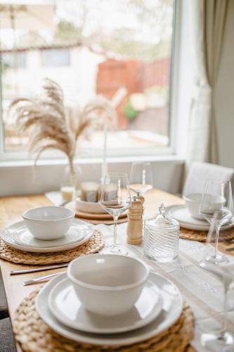 a table with plates and bowls and wine glasses at Serene Boho Retreat: White Oak Charm House 10ppl in Sheffield