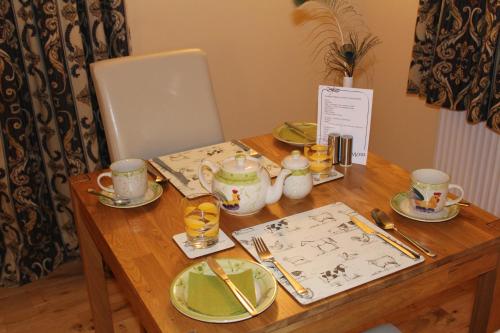 a wooden table with plates and cups on top of it at Shandon Farmhouse Bed and Breakfast in Drymen