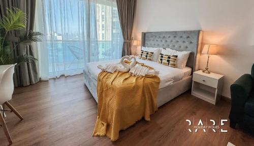 a bedroom with a bed with a table with towels on it at Rare Holiday Homes - Lake View - The Lago Vista Tower A - Dubai Production City - R1503 in Dubai