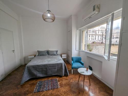 1 dormitorio con cama, silla azul y ventana en Apartamento central muy luminoso, en Buenos Aires