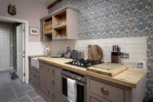 a kitchen with a stove and a counter top at Maltings Cottage in Barnard Castle
