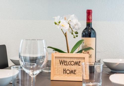 a bottle of wine and a vase with a flower on a table at HITrental Central Station Apartment in Zürich