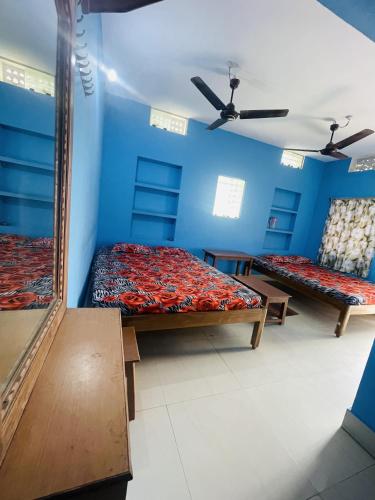 two beds in a room with blue walls at Chandrakanta Guest House in Puri