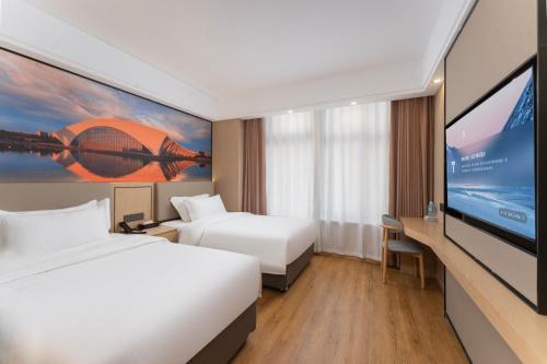 a hotel room with two beds and a flat screen tv at Shanghai Manhua Hotel-Provides free shuttle service to Disneyland in Shanghai