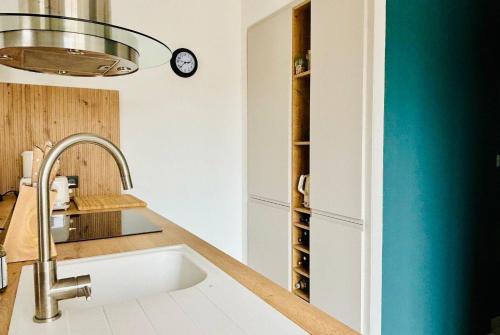 une cuisine avec un évier et une horloge murale dans l'établissement L Armada - Maison 3 Chambres - Terrasse Wifi, à La Rochelle