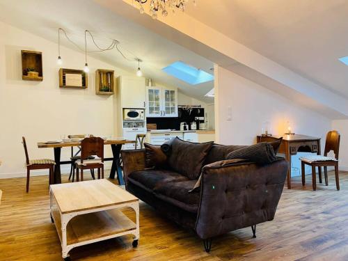 Il comprend un salon avec un canapé en cuir brun et une cuisine. dans l'établissement Le Boudoir de Thais, à La Rochelle