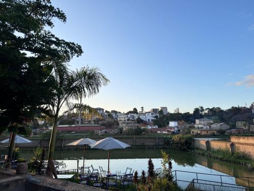 una piscina de agua con mesas y sombrillas y una ciudad en Suites&Stay, en Antananarivo