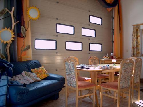 a living room with a table and a couch and windows at Abenteuerhof in Weißenbach