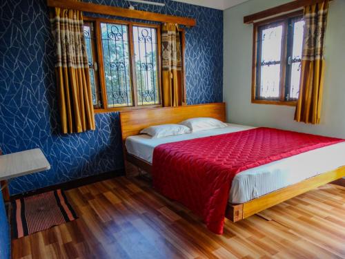 a bedroom with a bed with a red blanket and two windows at Misba Homestay Kodai in Kodaikānāl