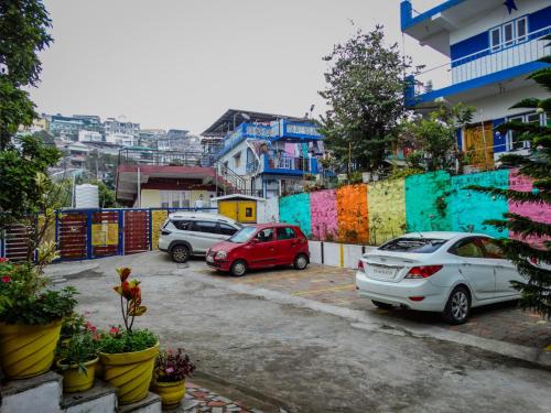 two cars parked in a parking lot next to a colorful fence at Misba Homestay Kodai in Kodaikānāl