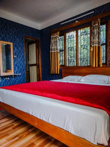 a bedroom with a large bed with blue walls and windows at Misba Homestay Kodai in Kodaikānāl