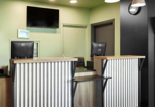 a lobby with two desks and a tv on the wall at B&B HOTEL Le Port Marly Saint Germain en Laye in Le Port-Marly
