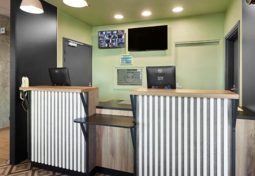 a lobby with two desks and a tv on the wall at B&B HOTEL Le Port Marly Saint Germain en Laye in Le Port-Marly