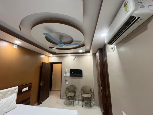 a bedroom with a ceiling fan and two chairs at Pond View By Basotel in Patna