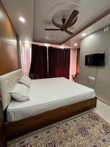 a bedroom with a large bed and a flat screen tv at Pond View By Basotel in Patna