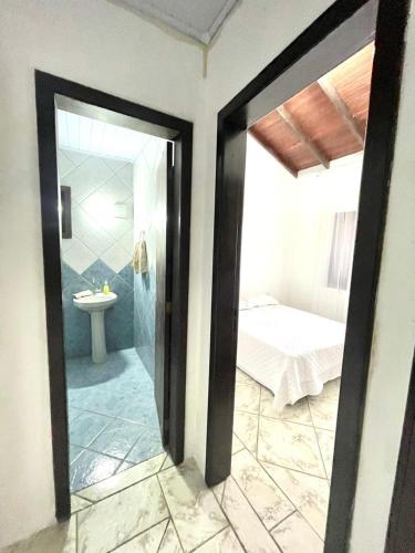 a room with a bathroom with a bed and a mirror at Casa da Lagoa in Tramandaí