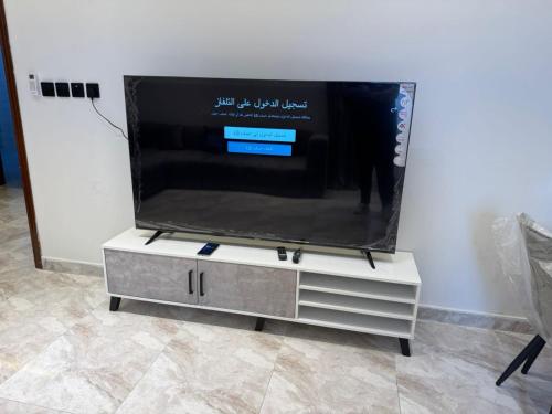 a flat screen tv sitting on top of a tv stand at جود ان للشقق الفندقية in Aţ Ţunḑubāwī