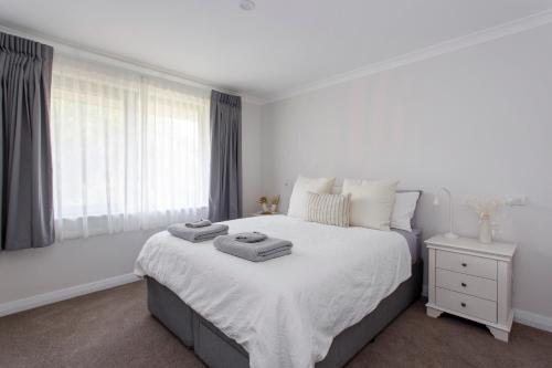 a white bedroom with a bed with two towels on it at Maylands Riverside City Retreat in Perth