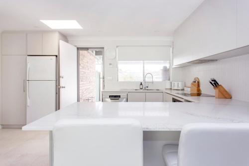 a white kitchen with white appliances and white counters at Maylands Riverside City Retreat in Perth