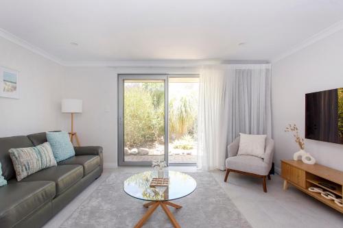 a living room with a couch and a table and a tv at Maylands Riverside City Retreat in Perth