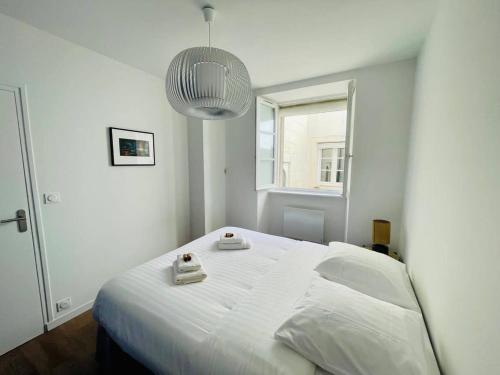 une chambre avec un lit blanc avec deux serviettes dessus dans l'établissement Le Petit Minage - Charmant T2 Hypercentre - Wifi, à La Rochelle