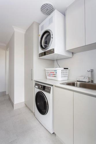 a white kitchen with a washing machine and a sink at Maylands Riverside City Retreat in Perth