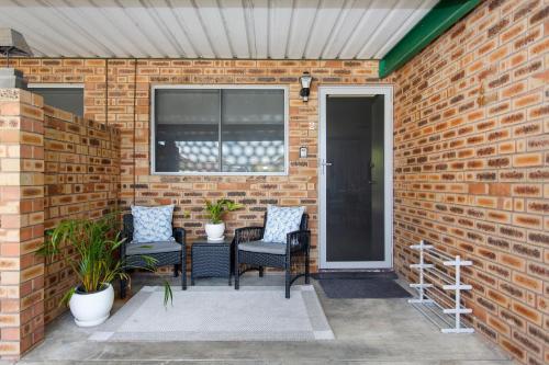 a patio with two chairs and a table on a brick wall at Maylands Riverside City Retreat in Perth