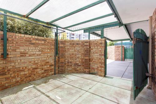 a patio with a brick wall and a glass door at Maylands Riverside City Retreat in Perth