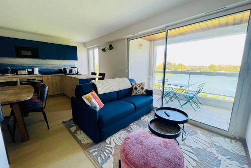 un salon avec un canapé bleu et une cuisine dans l'établissement Le Cottage du Lac - Terrasses Wifi et Parking, à La Rochelle