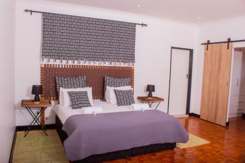 een slaapkamer met een groot bed met kussens bij Casa Linda in Harare