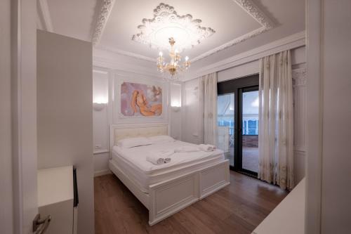 a white bedroom with a bed and a chandelier at Luxury Apartment in Sarandë