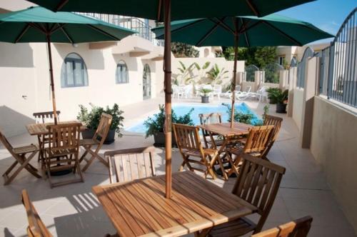 um pátio com mesas de madeira e cadeiras com guarda-sóis em Hotel Kappara em San Ġwann